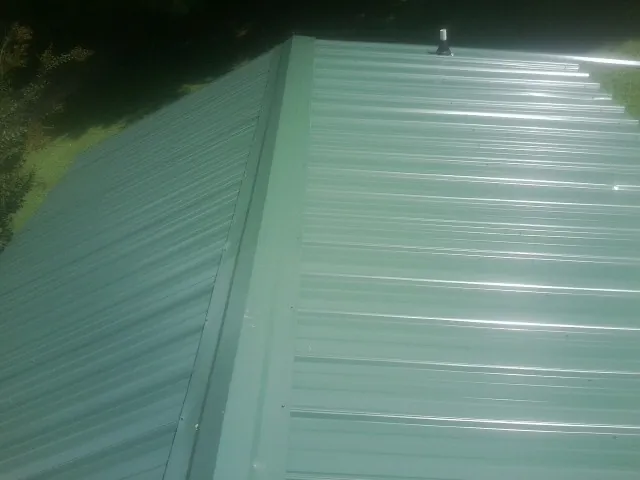 New green metal panels meeting at the ridge of a roof — Flat Roof Repair work by our crew in Tetonia