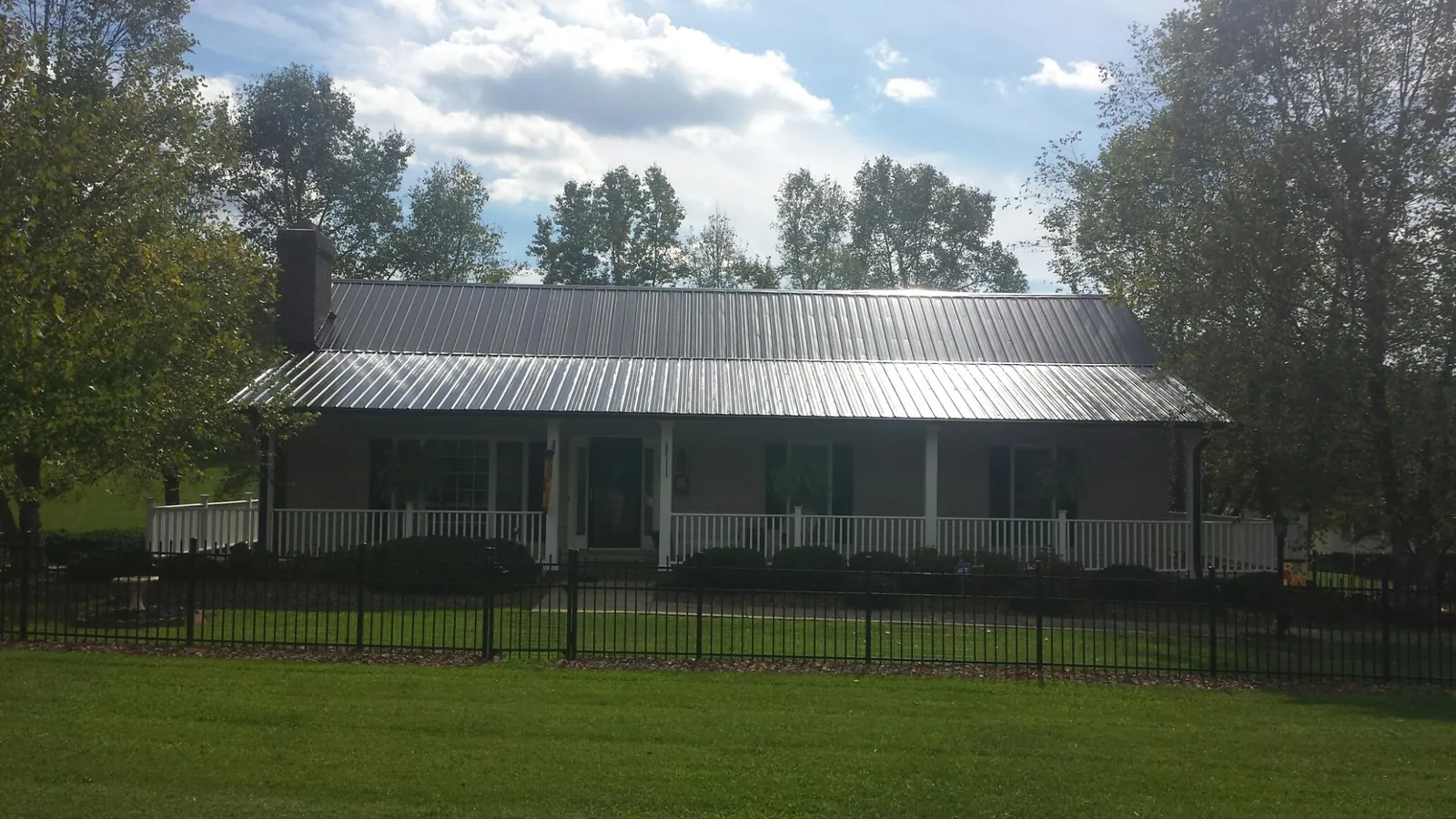 Gray metal roof on a brick ranch with a full width front porch — Gutter Guard Installation work by our crew in Tetonia