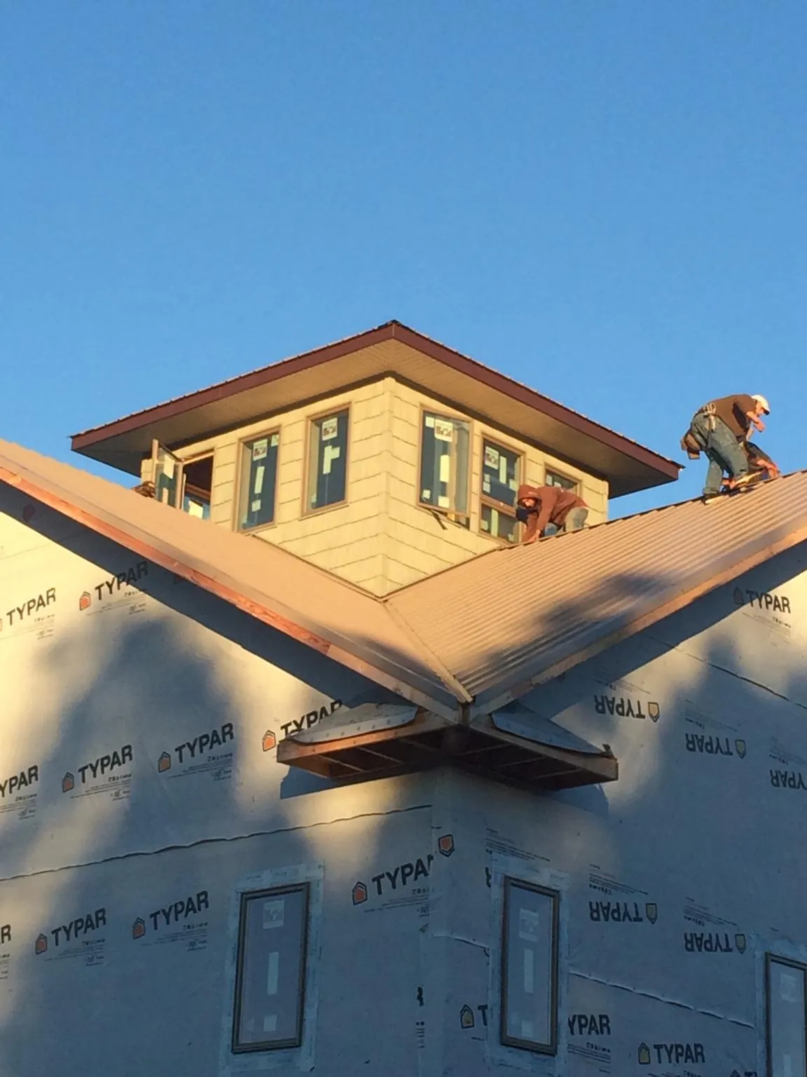Roofers working around a rooftop cupola on a new metal roof at sunset — Roof Waterproofing in Tetonia by Roofing Brothers